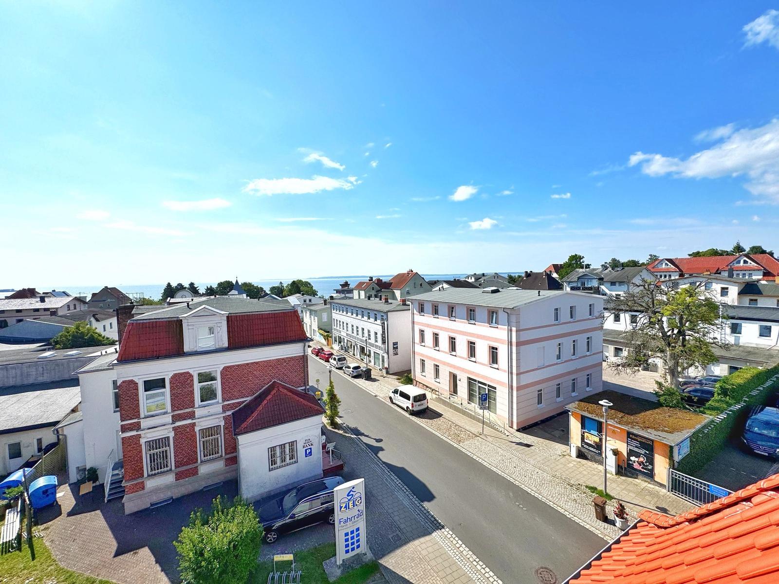 Städtischer Blick mit Straßen, Häusern und Meerblick im Hintergrund.