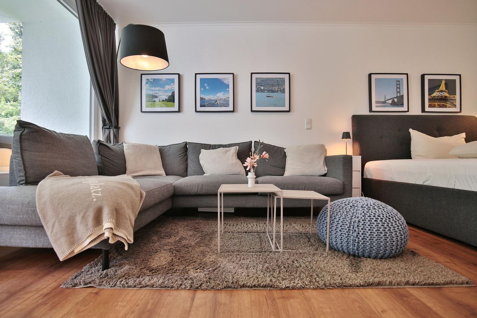 Wohnzimmer mit Sofa, Bett und Wandbildern.