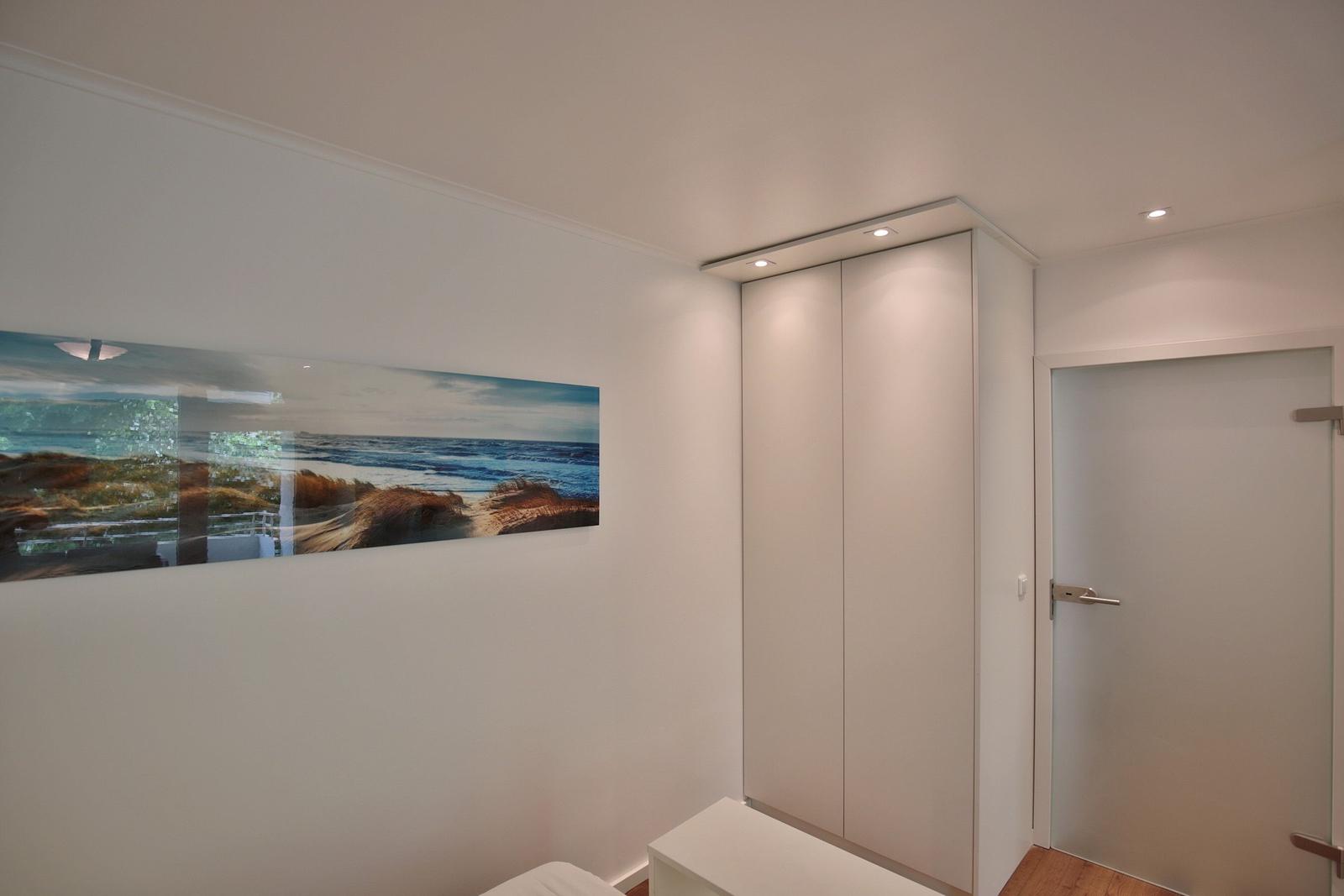 Schlafzimmer mit Kleiderschrank, Tür und Wandbild am Schrank.