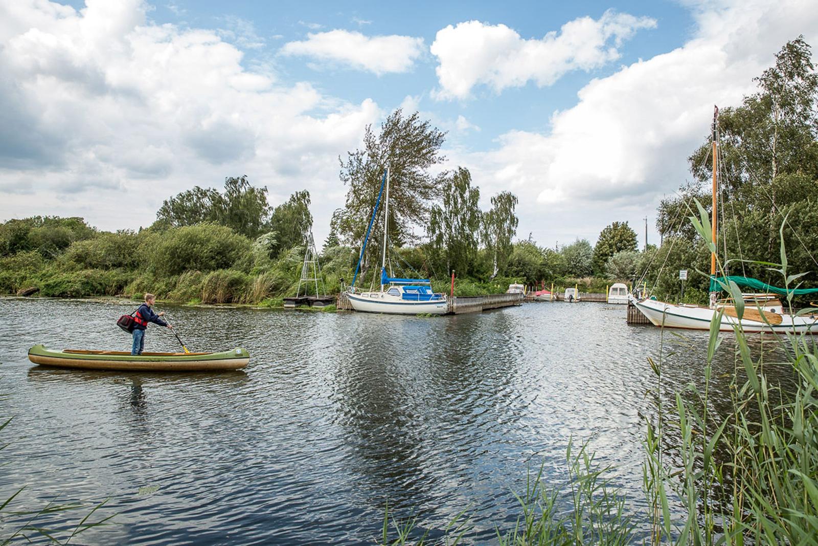 Ein Kajakfahrer auf einem Kanal mit Anlegestellen und Booten.