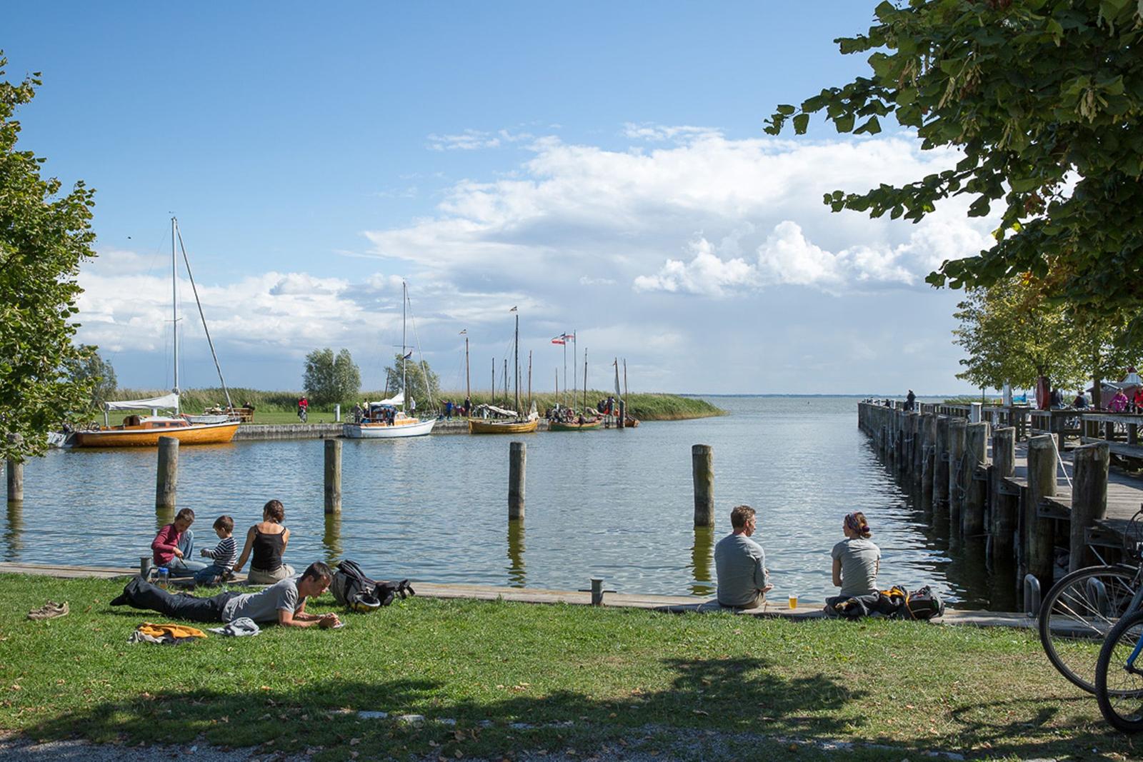 Besucher genießen den Blick auf das Wasser und Boote am Ufer.