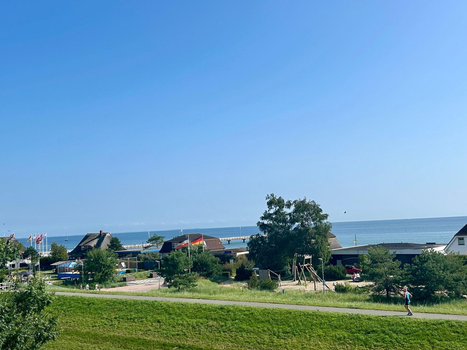 Meerblick mit Strandpromenade und Spielplatz im Vordergrund.