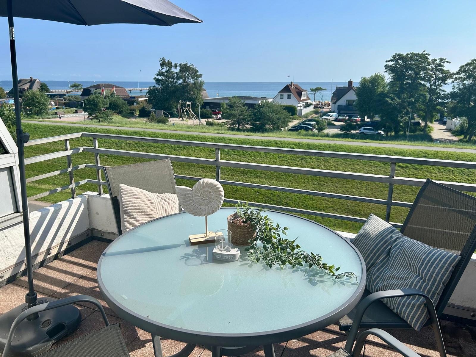 Terrasse mit Tisch, Stühlen und Blick aufs Meer
