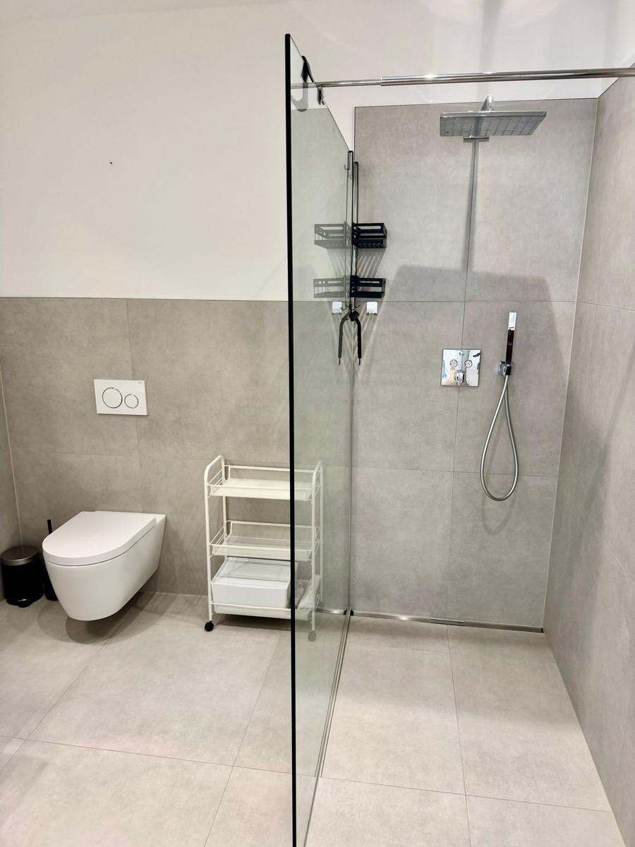 Moderne Dusche mit Glaswand und Toilette in minimalistischem Badezimmer.