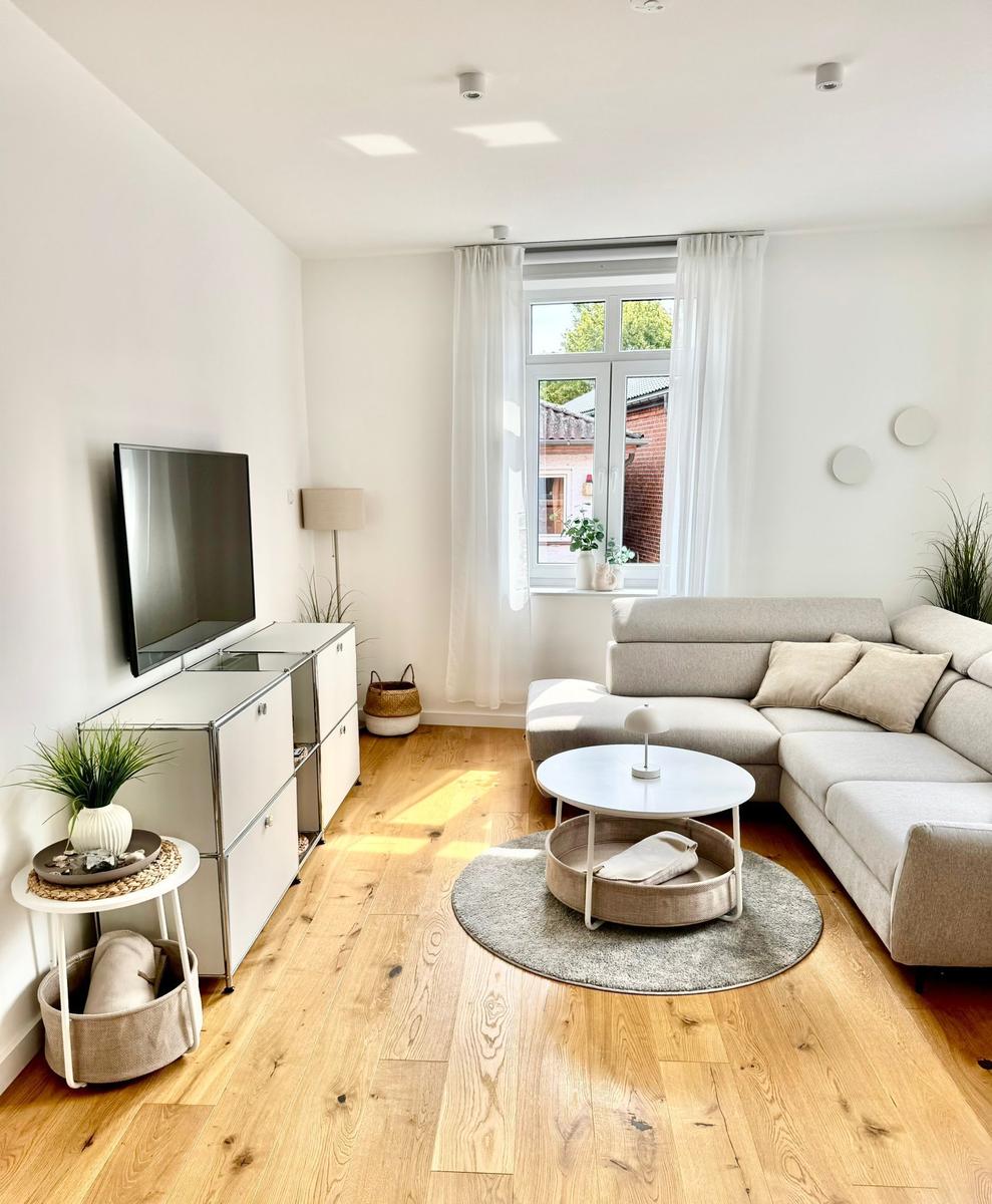 Wohnzimmer mit Sofa, Couchtisch und Fernseher an der Wand.