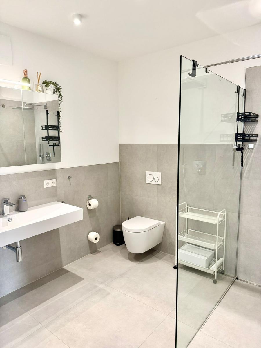 Moderne Badewohnung mit Dusche, Toilette und Waschbecken.