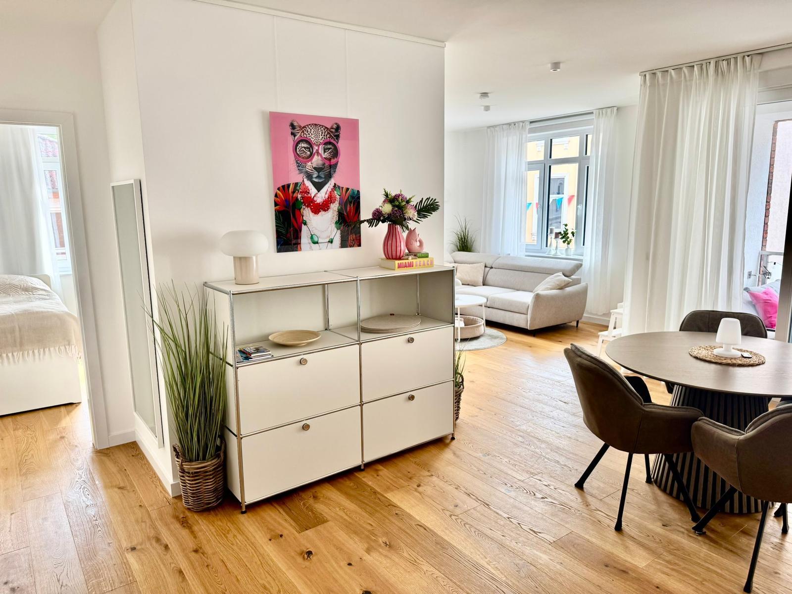 Wohnung mit Essbereich, Wohnzimmer und Schlafzimmer. Holzboden und helles Interieur.