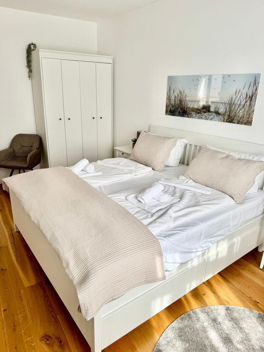 Schlafzimmer mit Doppelbett, Kleiderschrank und Wandbild.