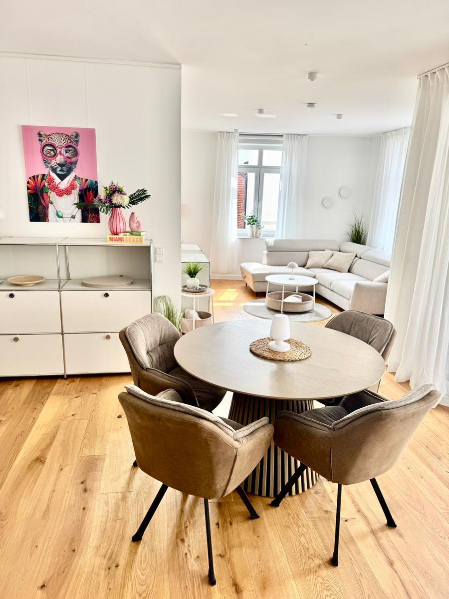 Essbereich mit runder Tisch und vier Stühlen. Wohnbereich mit Sofa und Fenster.