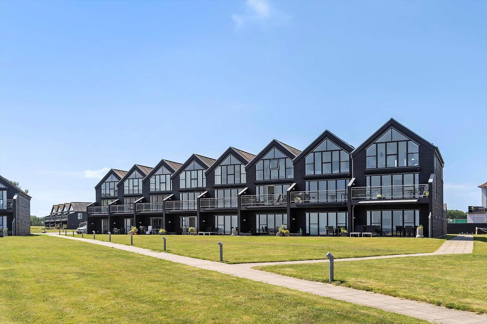 Reihe moderner Holzgebäude mit Balkonen und großen Fenstern auf grünem Rasen.