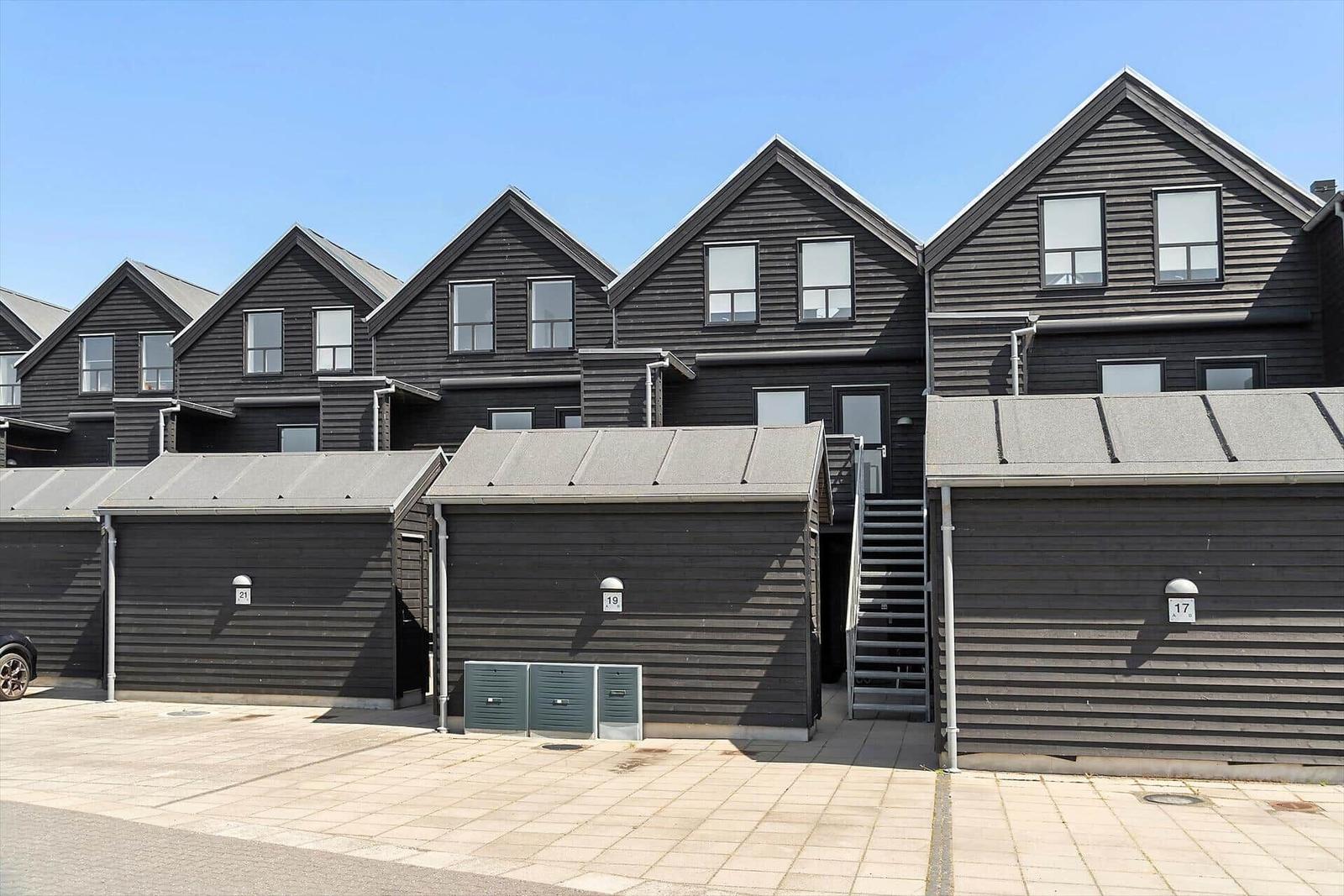 Reihe moderner Holzhauser mit Garagen und Außentreppe.