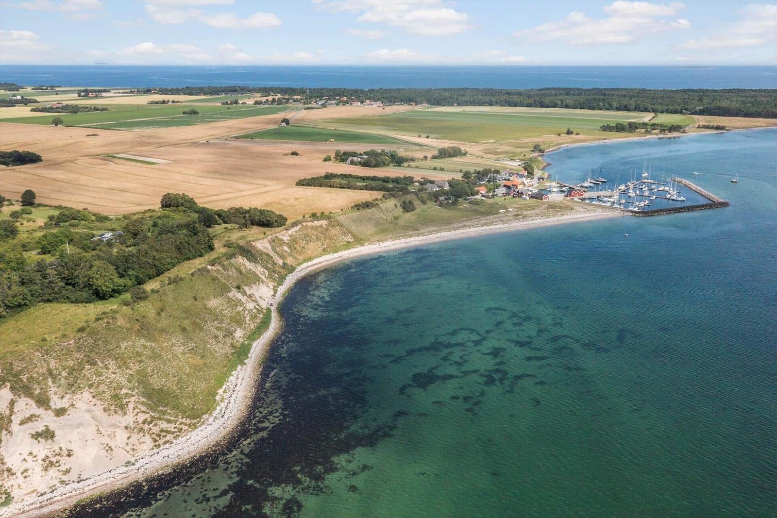 Hafen mit Booten an Küste mit Feldern und Wald