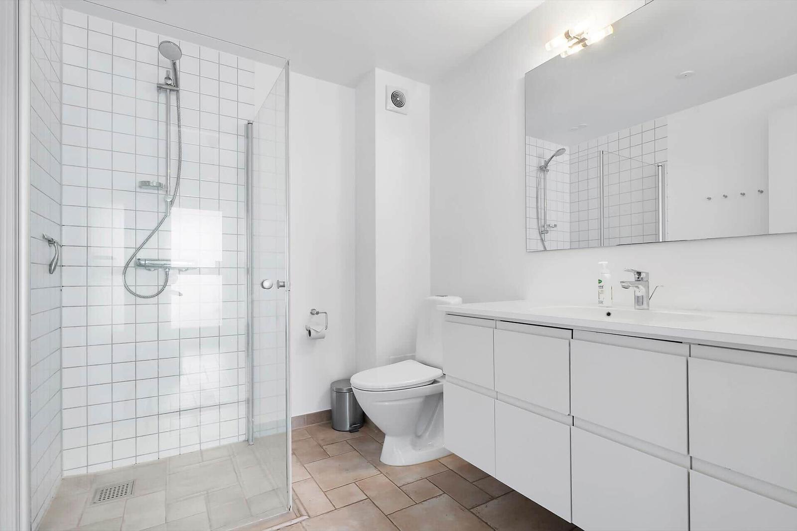 Badezimmer mit Dusche, Toilette und Waschbecken mit Spiegel.