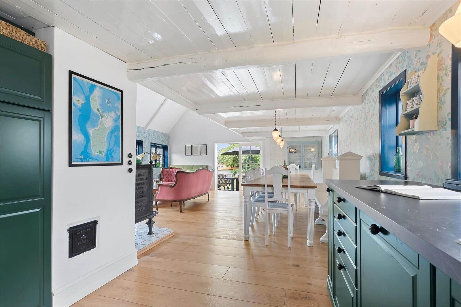 Küche mit Essbereich und Wohnbereich mit Holzboden und weißen Deckenbalken.