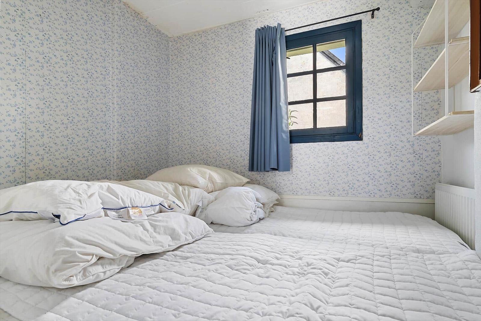 Schlafzimmer mit Bett, Fenster und Wandverkleidung.