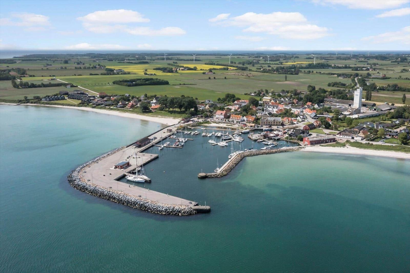 Hafen mit Booten, Strand und kleinem Dorf an der Küste.