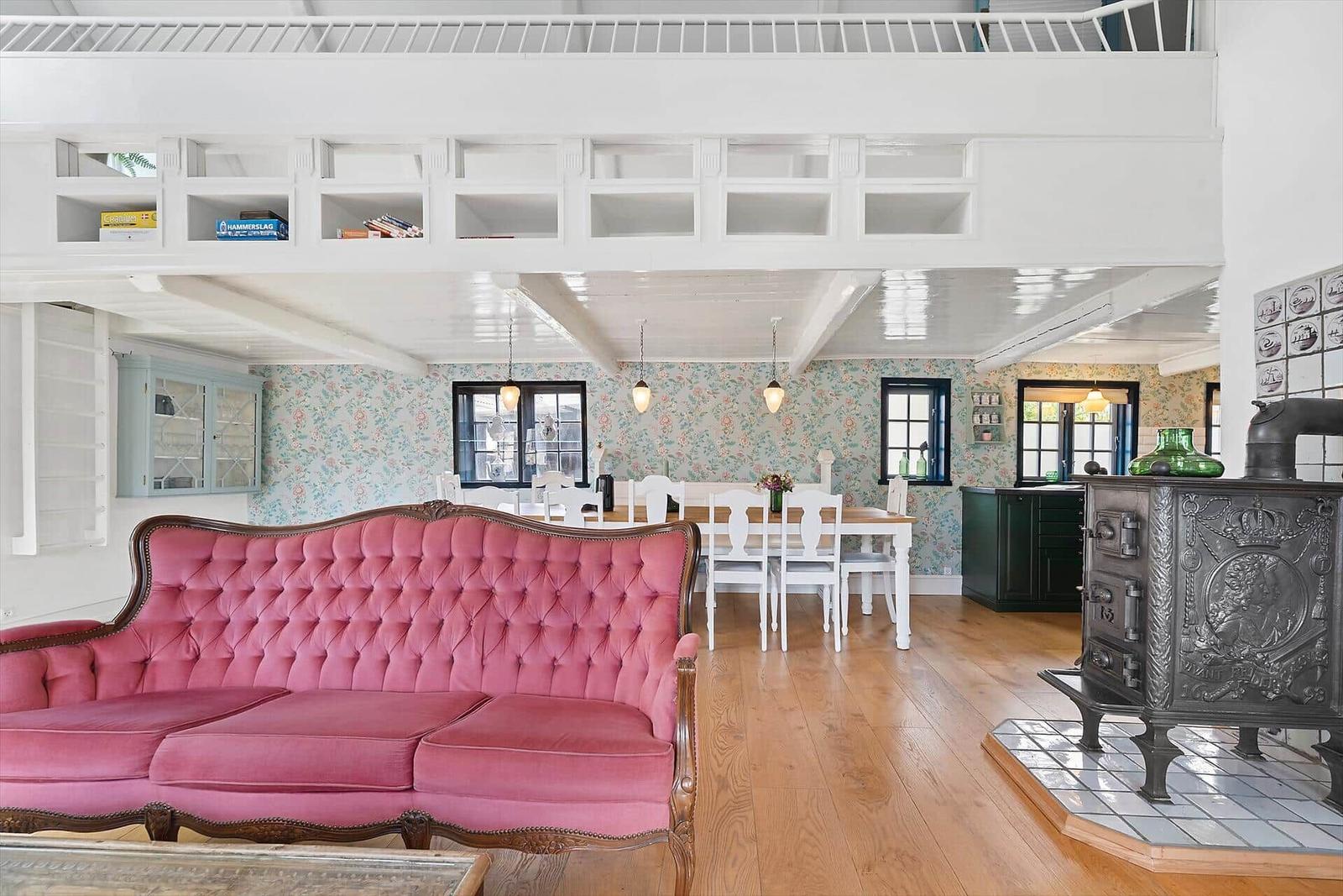 Ein Wohn- und Essbereich mit rosa Sofa, Holzboden und Hochbett.