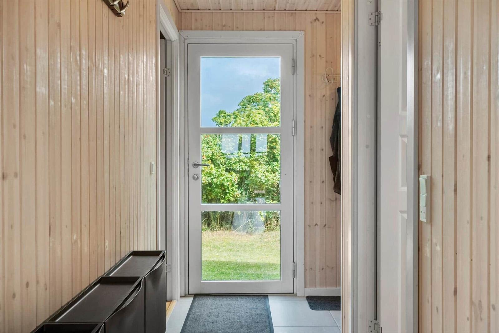 Eingangsbereich mit Holzwand und Tür zum Garten.