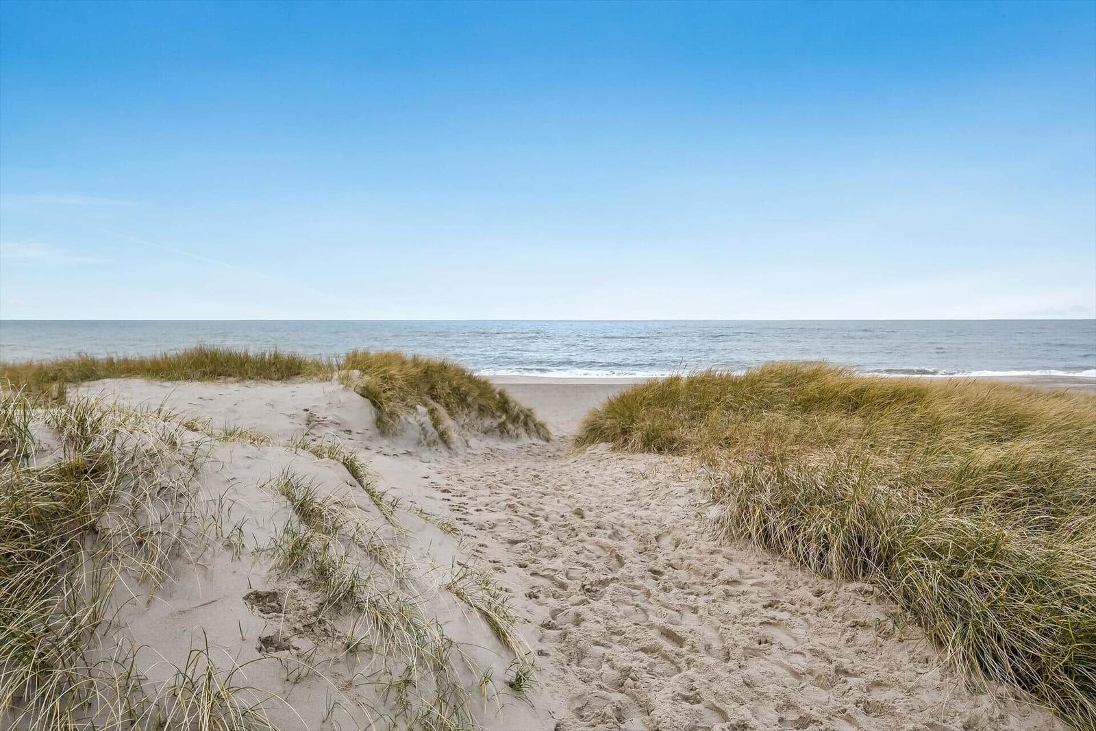 Sandweg führt durch Dünen zum Strand und Meer.