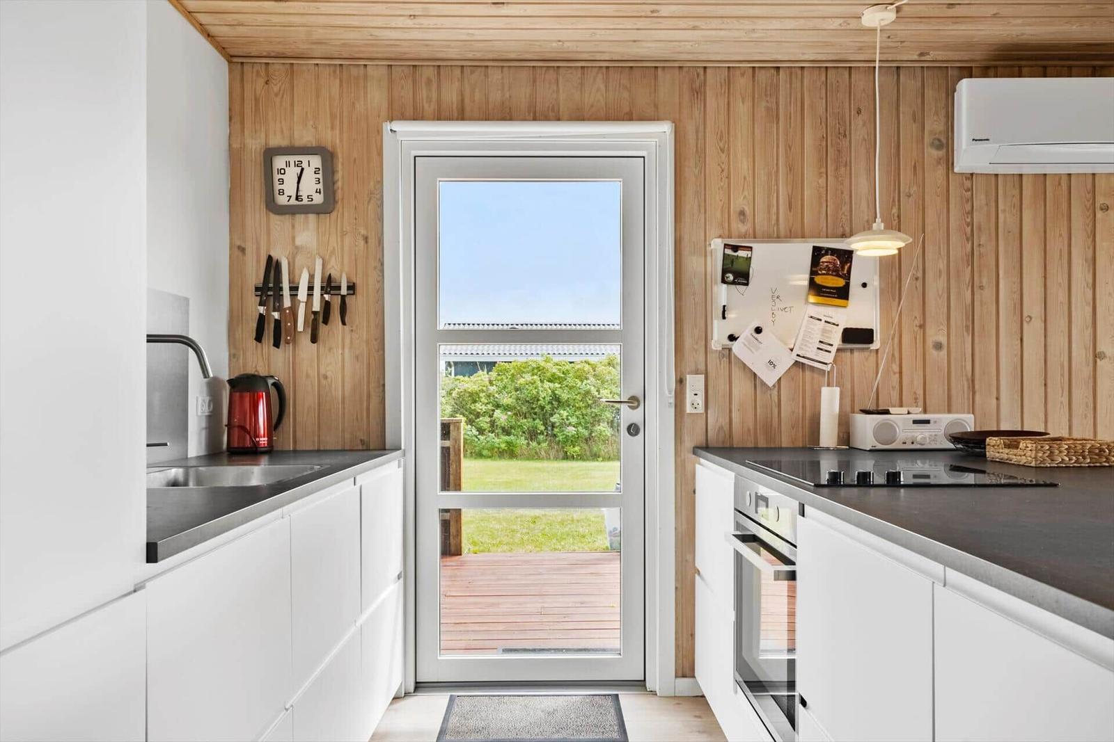 Küche mit Holzwand, Tür zum Garten und Küchengeräten.