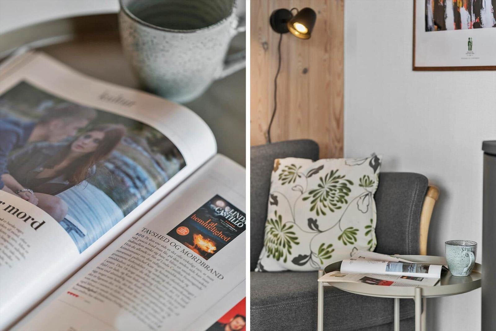 Ein grauer Sessel mit Kissen und einem Beistelltisch mit Tasse und Zeitung.