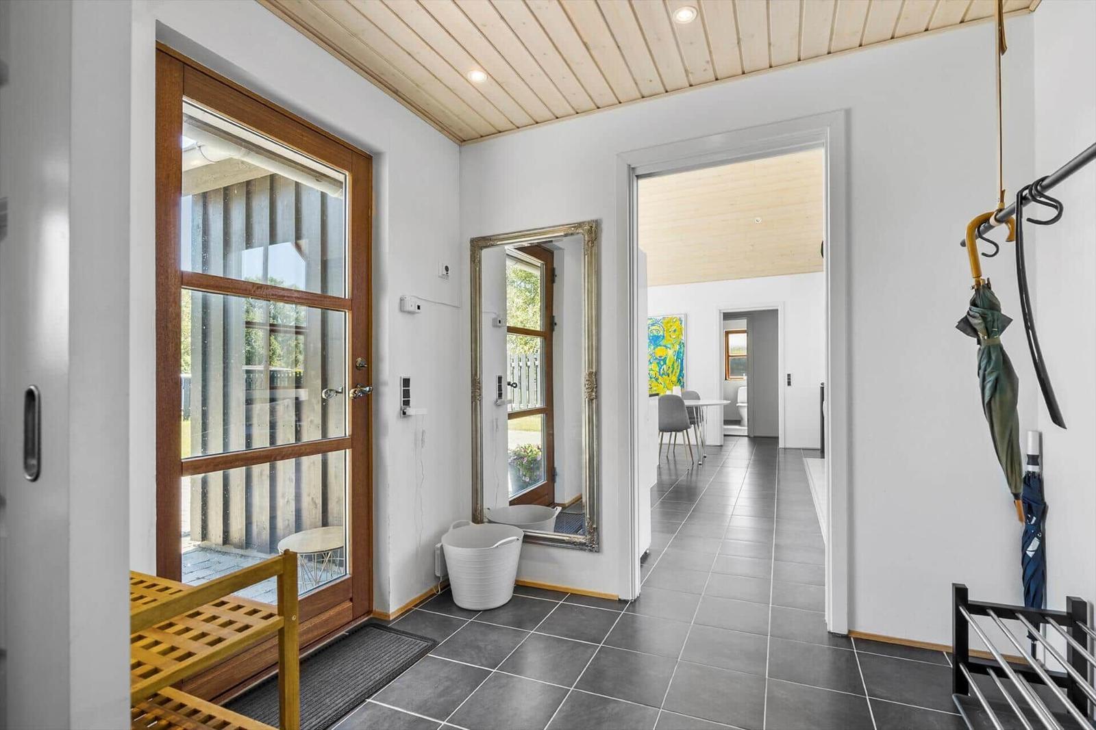 Eingangsbereich mit Holzdecke, Spiegel und Tür zum Garten.