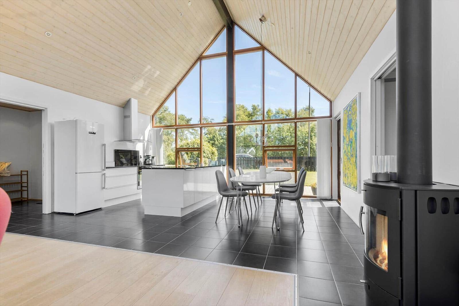 Moderne Küche mit Essbereich und Kamin unter hohem Holzdach