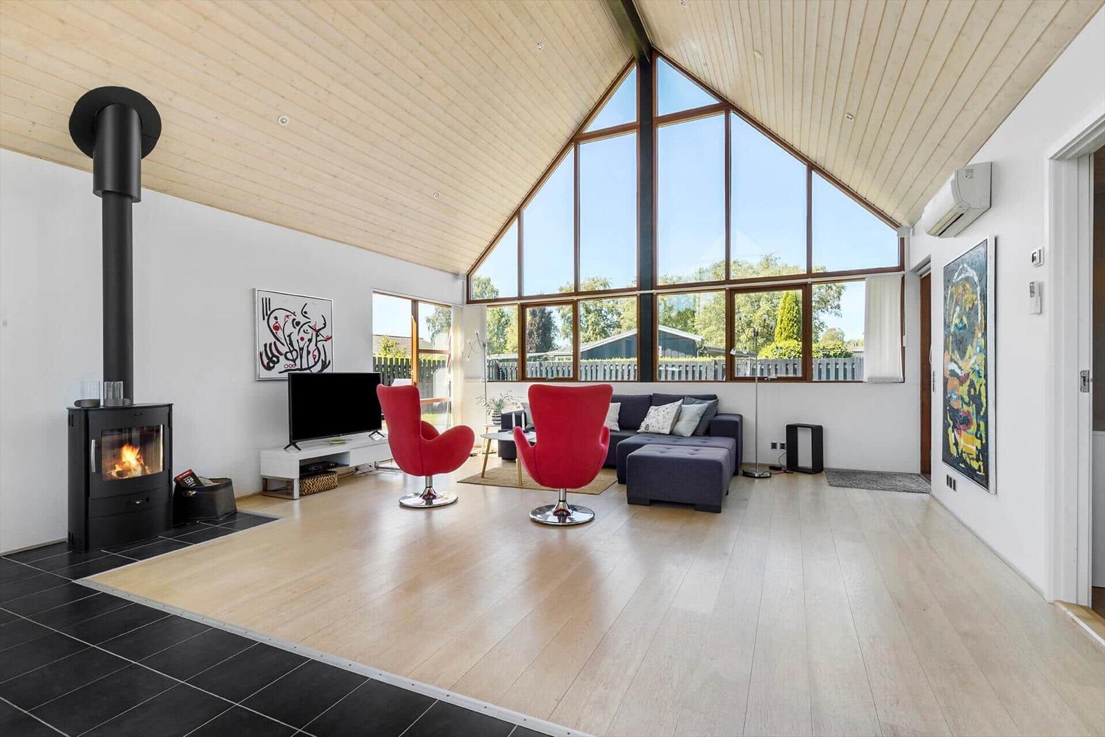 Wohnzimmer mit Kamin, roten Sesseln und großem Fenster