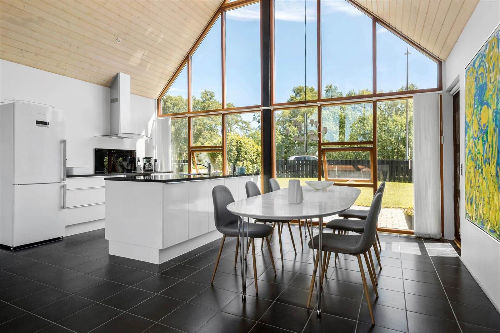 Moderne Küche mit Essbereich und großem Fensterblick auf Garten.