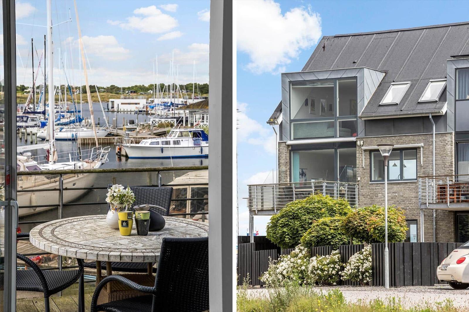Terrasse mit Tisch und Stühlen. Blick auf Hafen mit Booten. Modernes Haus mit Balkon.