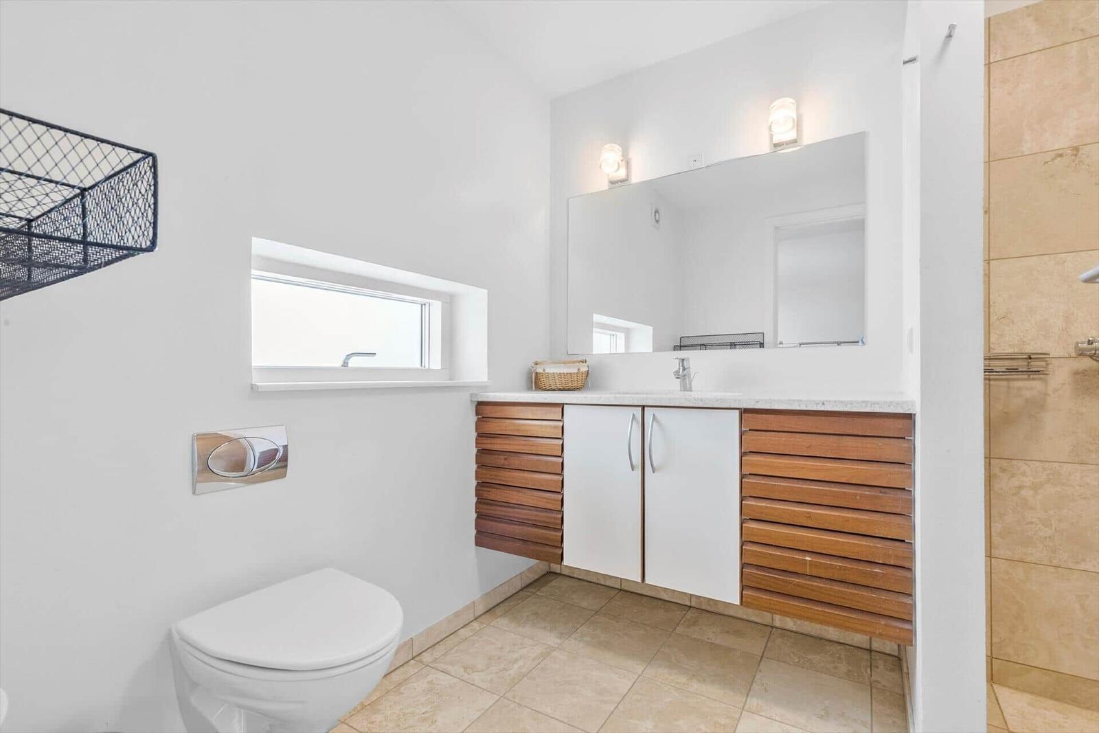 Badezimmer mit Waschbecken, Spiegel, Toilette und Dusche.