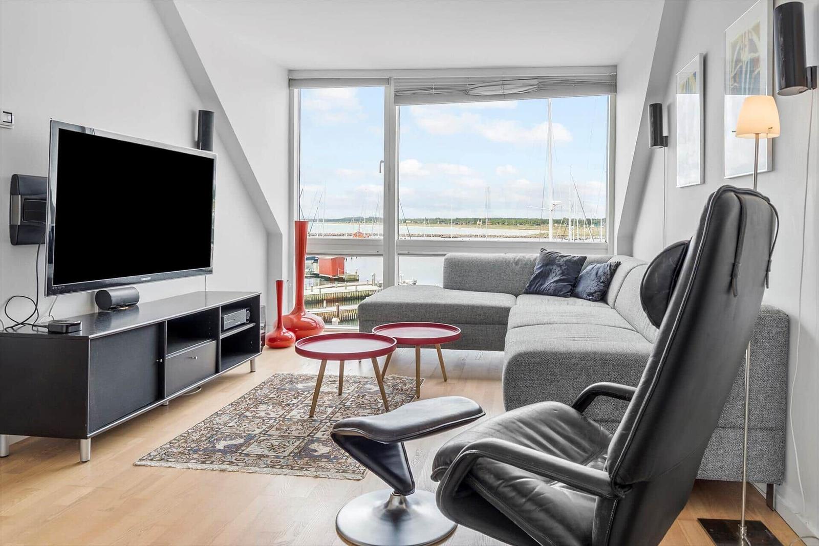 Wohnzimmer mit Sofa, Fernseher und Aussicht auf Hafen.
