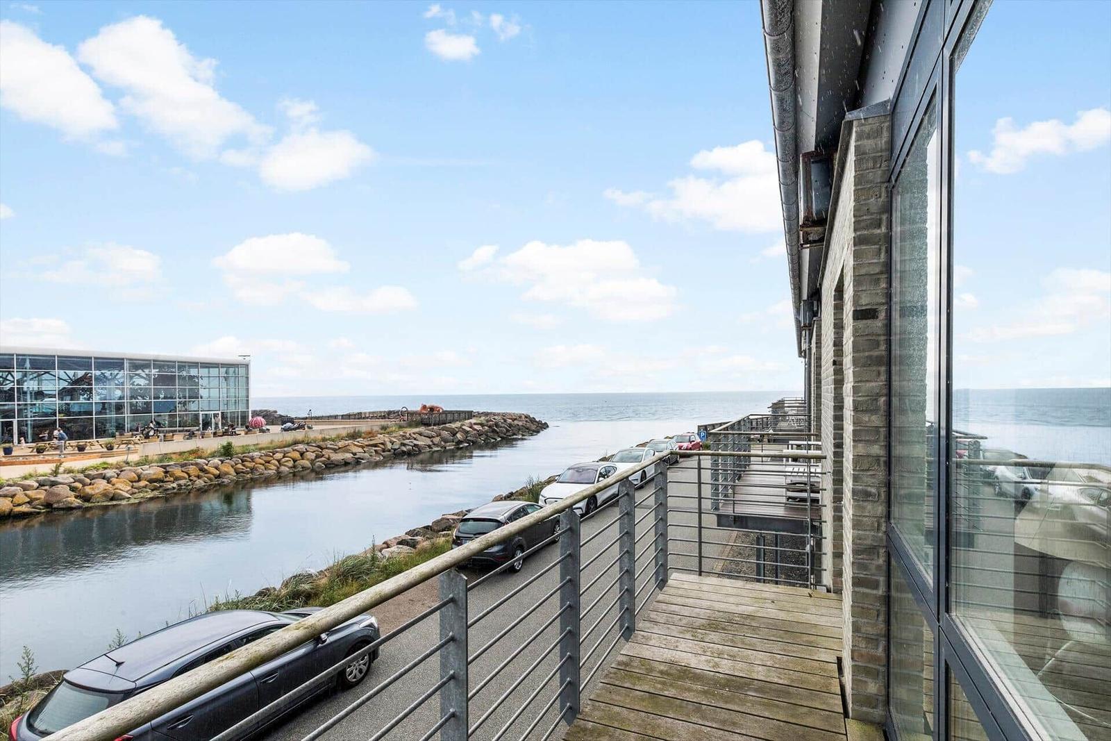 Terrasse mit Blick auf Hafen und Meer. Autos parken entlang des Ufers.