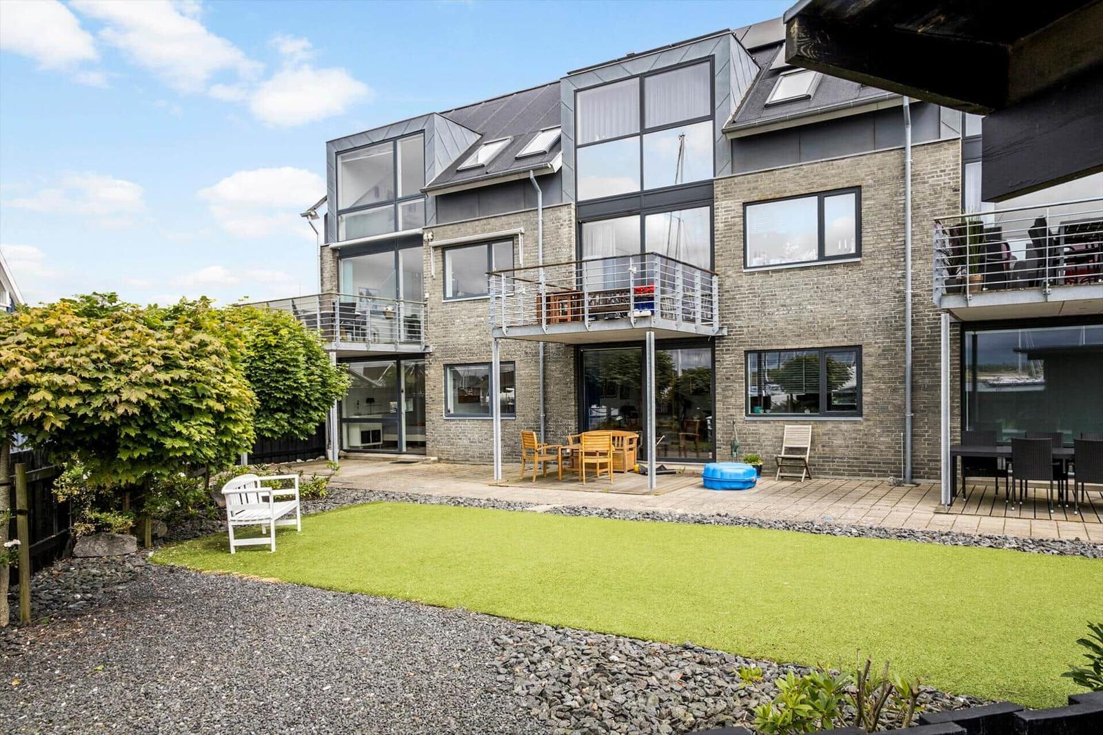 Moderne Villa mit Balkon, Terrasse und grünem Gartenbereich.