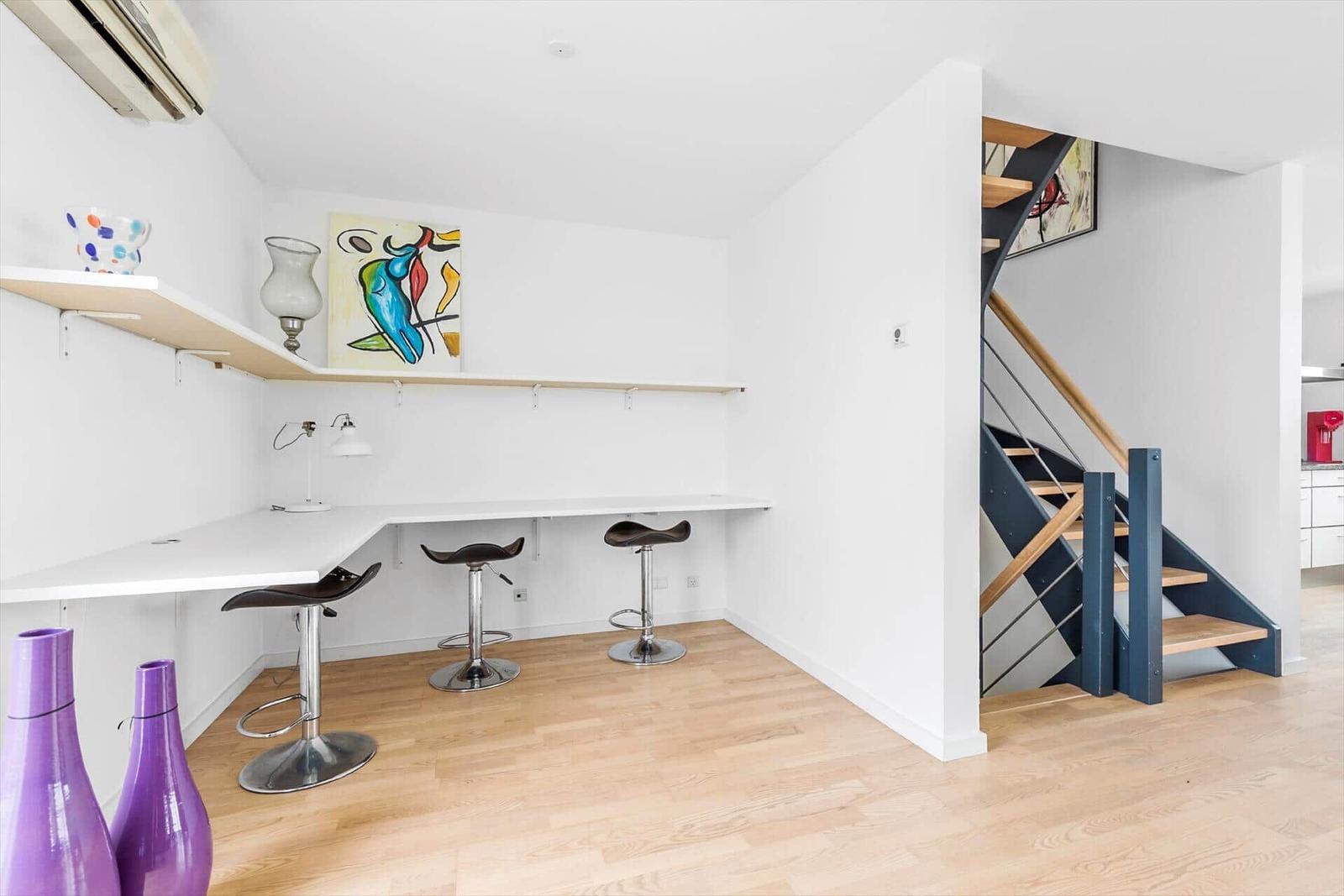 Helle Arbeitsfläche mit drei Barhockern und Treppe zur oberen Etage.