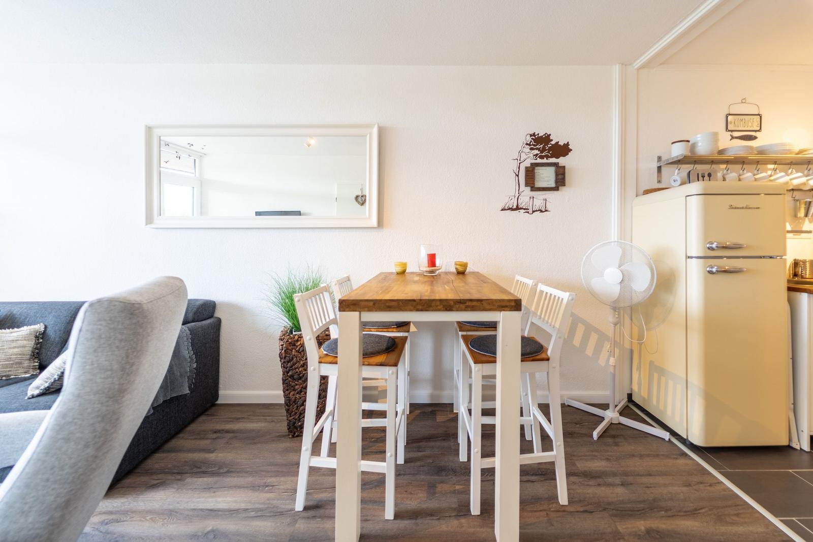 Essbereich mit Tisch, Stühlen und Küchenbereich mit Kühlschrank.