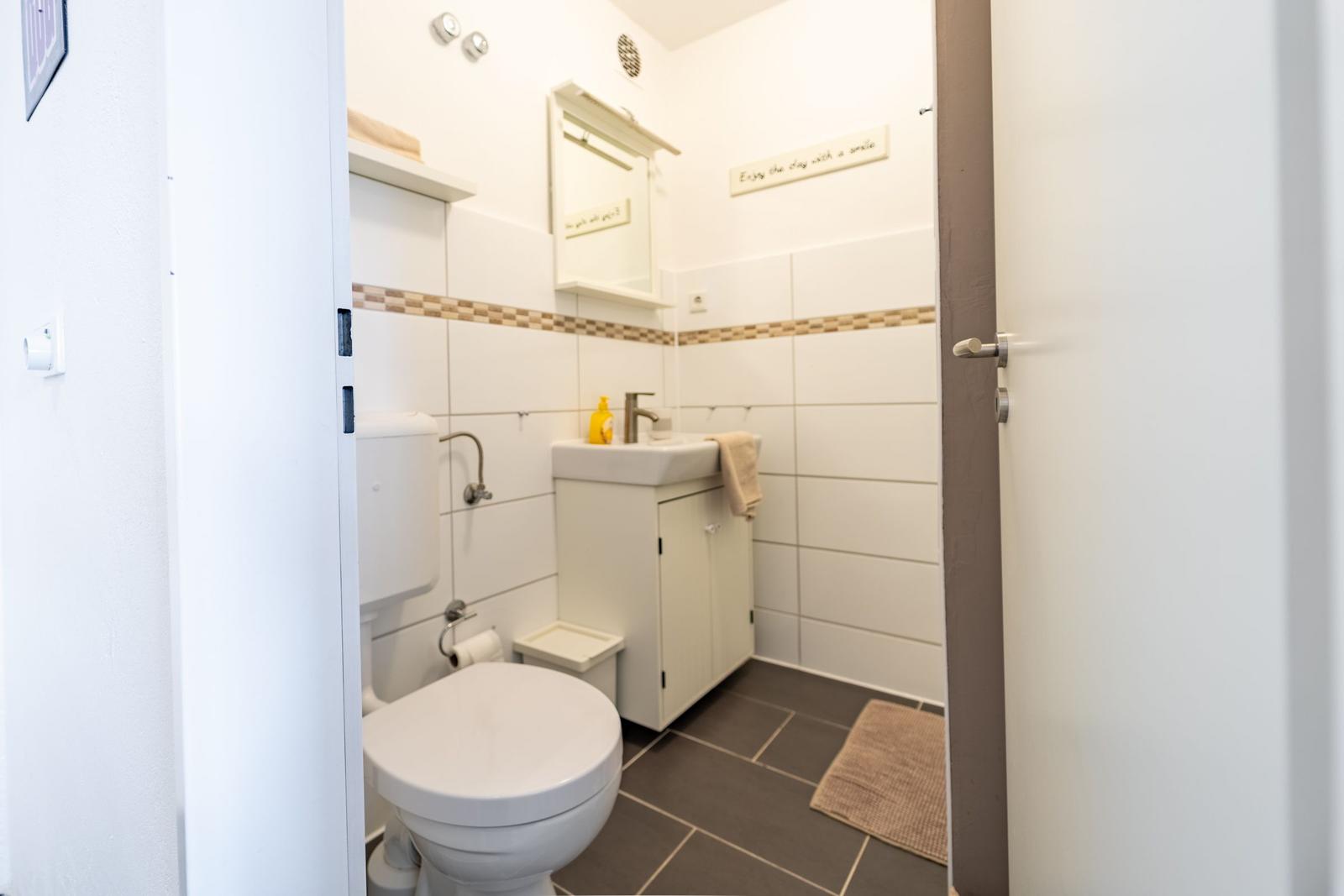 Badezimmer mit Toilette, Waschbecken und Handtuch