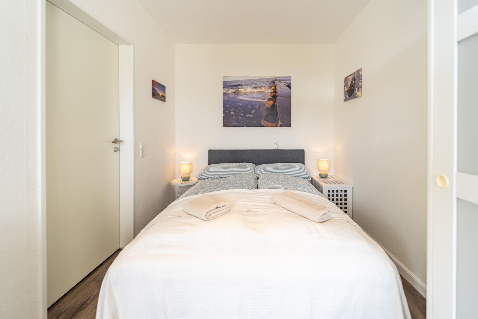 Schlafzimmer mit Doppelbett, Nachttischen und Wandbildern.