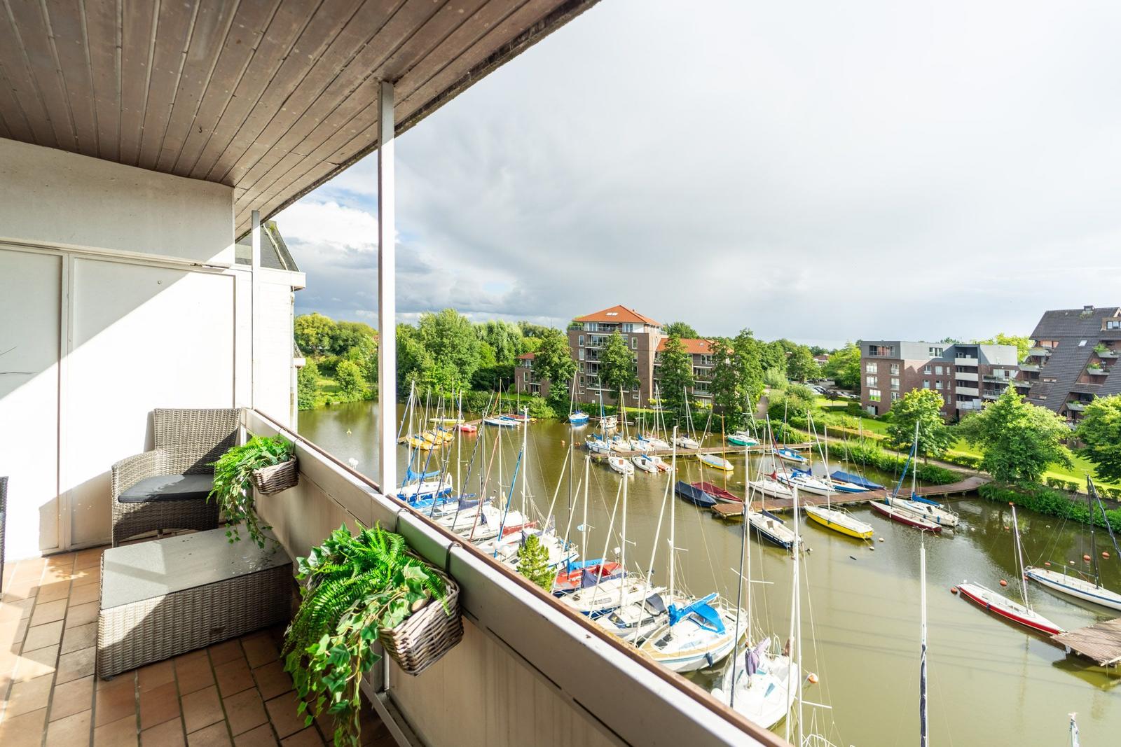 Terrasse mit Sitzgelegenheit und Blick auf Hafen mit Booten.