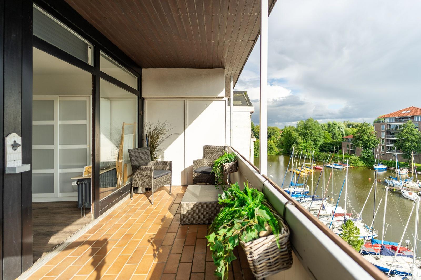 Terrasse mit Sitzgelegenheit und Blick auf einen Bootssteg.