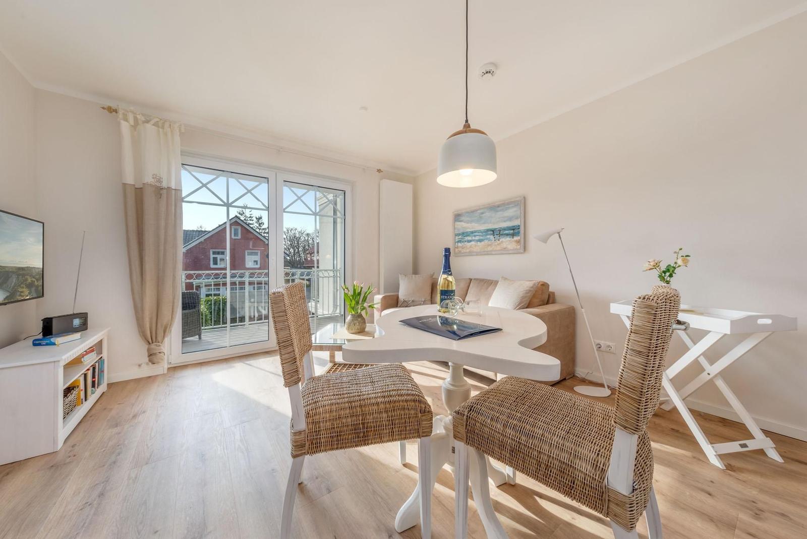 Wohnbereich mit Esstisch, Sofa und Balkontür.