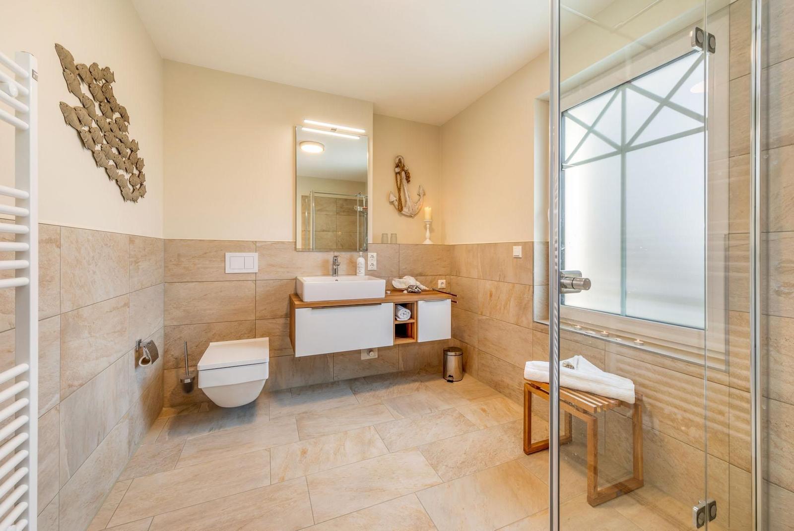 Badezimmer mit Dusche, Waschbecken und Toilette. Wandverkleidung aus Stein und Holz.