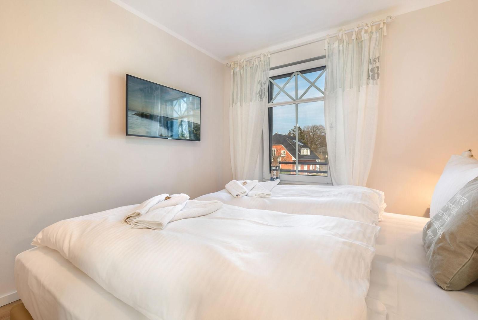 Zwei Betten mit weißen Bettwäsche, Fernseher und Fenster mit Blick.