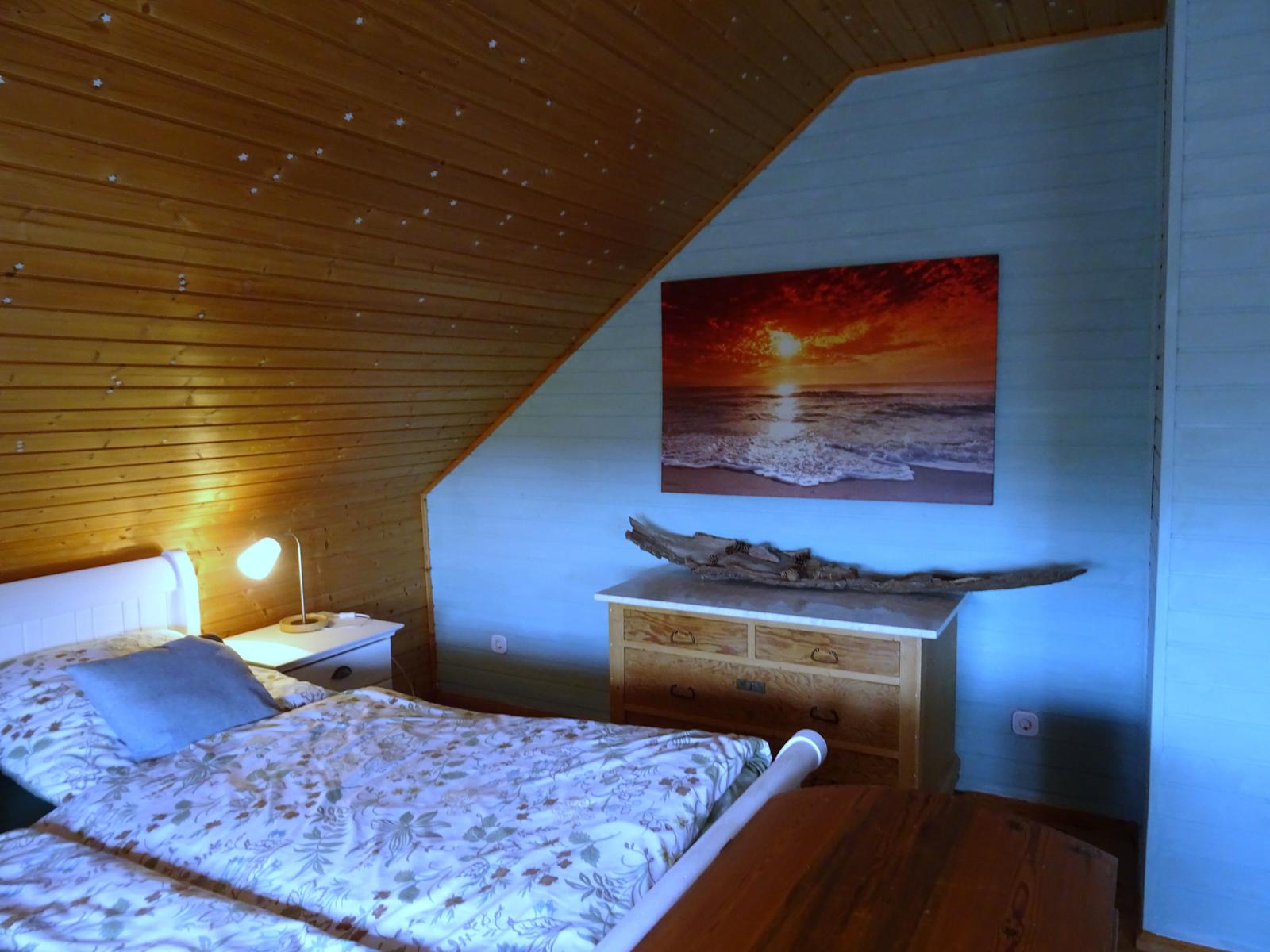 Schlafzimmer mit Bett, Nachttisch und Schrank. Decke mit Sternen, Wandbild und Holzdekoration.