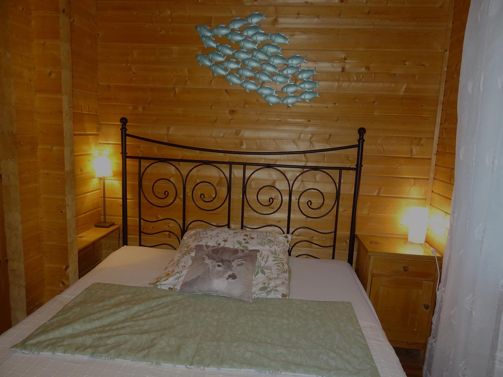 Schlafzimmer mit Holzwand, Metallbett und Fischdekoration.
