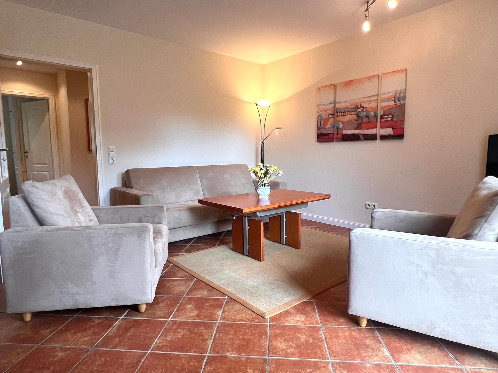 Wohnzimmer mit Sofa, zwei Sesseln und Tisch auf Teppich