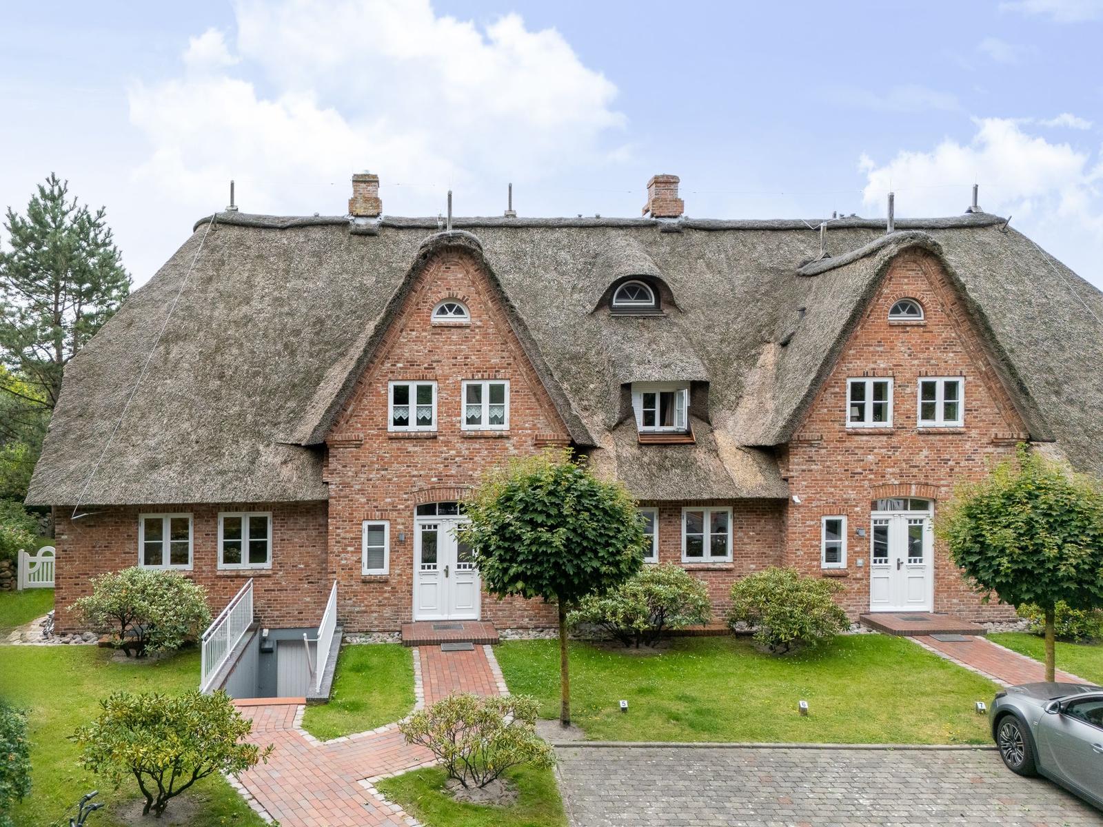 Rotes Backsteingebäude mit Strohdach und weißen Fenstern.