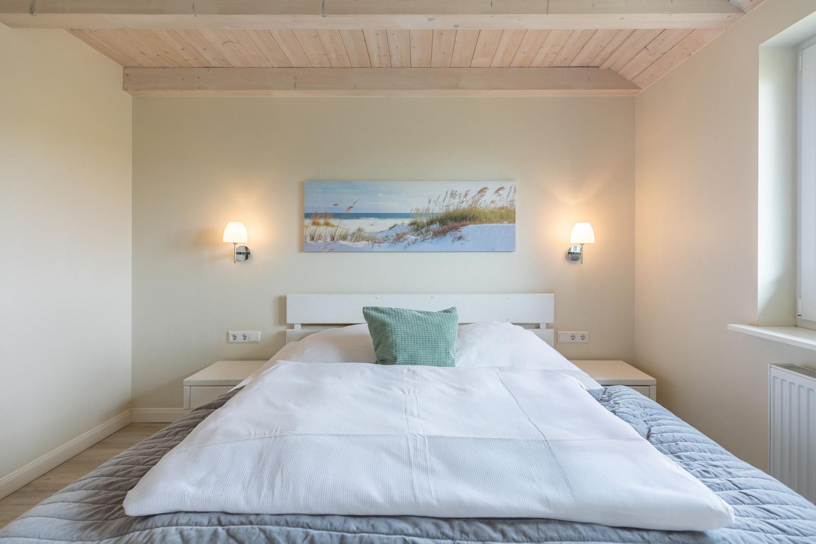 Schlafzimmer mit Bett, Wandbild und Stehlampen.