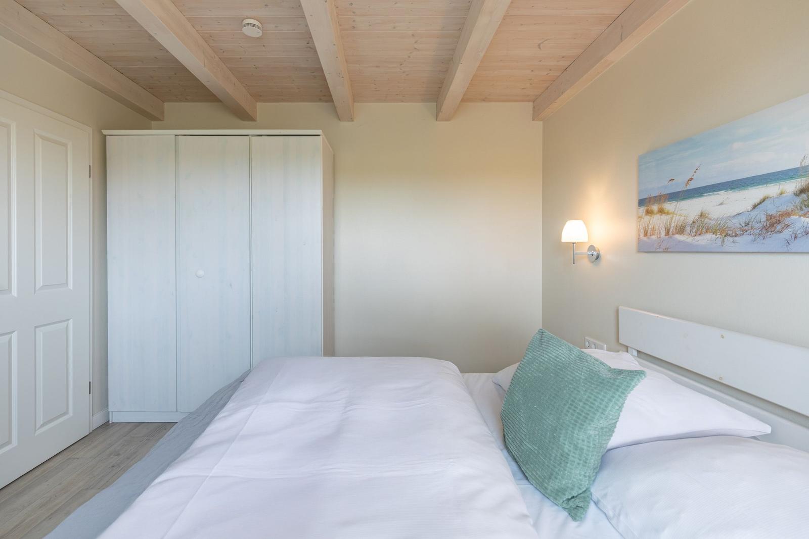 Schlafzimmer mit Bett, Kleiderschrank und Wandbild