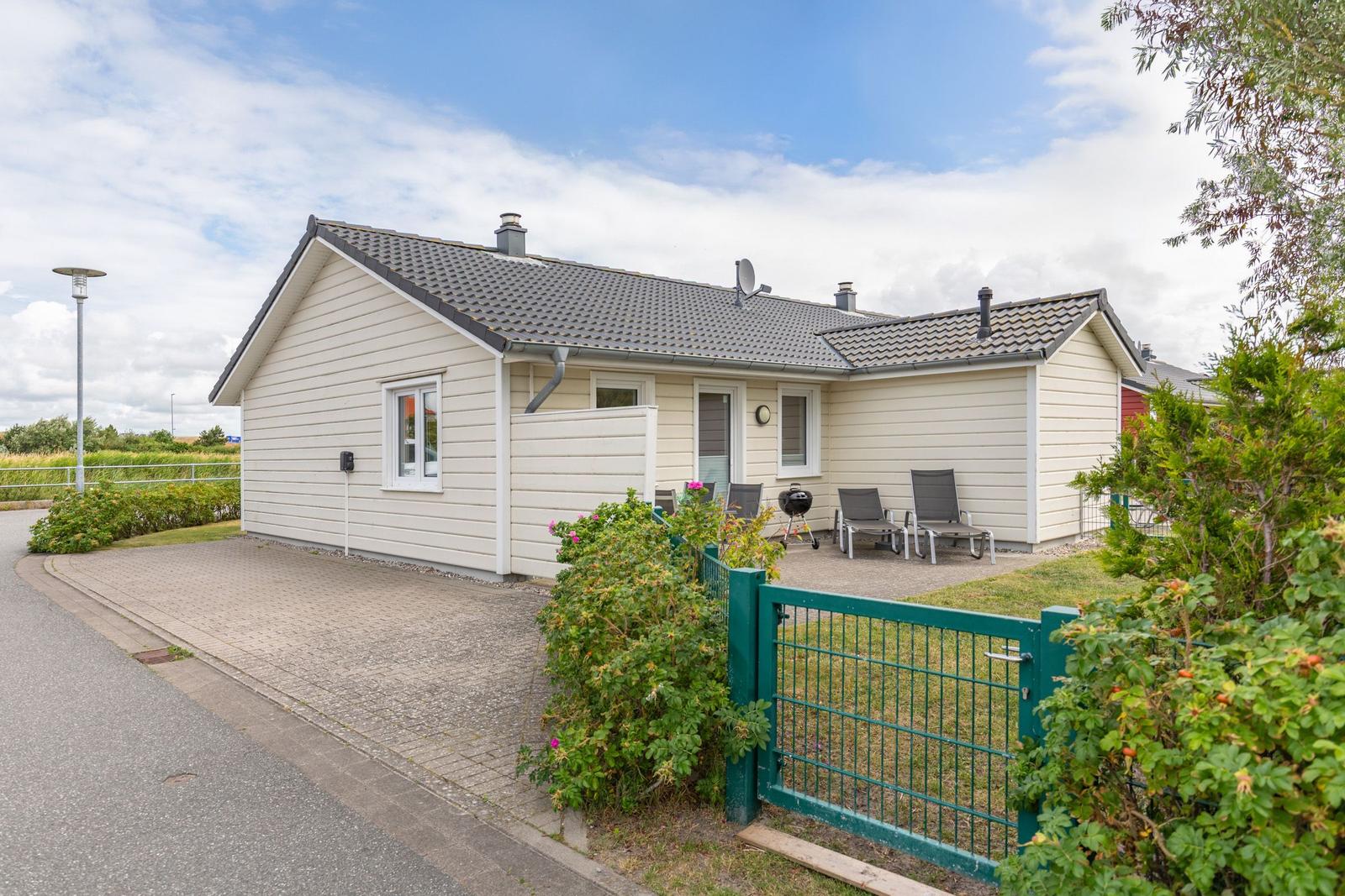 Wohnhaus mit Terrasse, Grill und Gartenzaun. Hinterhof mit Sitzgelegenheiten.